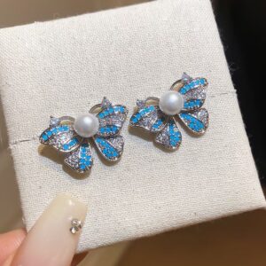 Blue crystal bow stud earrings with a faux pearl center and sterling silver setting